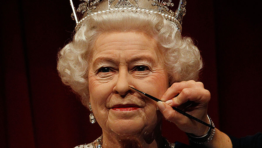 Сотрудник музея с кисточкой и фигурой британской королевы Елизаветы II, 2012 год