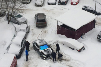 Жители Москвы пытаются вытащить из сугроба автомобиль, 4 февраля 2018 года