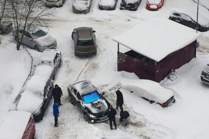 Жители Москвы пытаются вытащить из сугроба автомобиль, 4 февраля 2018 года