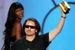 Вокалист U2 Боно с музыкальной наградой, врученной топ-моделью Наоми Кэмпбелл, во время церемонии вручения NRJ в Каннах, 2005 год