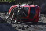 Украинские военнослужащие переворачивают поврежденный автомобиль в Запорожье, Украина, 8 мая 2024 года
