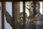 16 июня 2015 года. Свергнутый президент Египта Мухаммед Мурси приветствует адвокатов и людей из-за решеток после своего приговора в суде 
