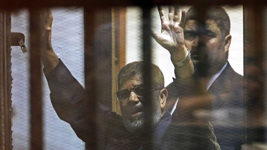 16 июня 2015 года. Свергнутый президент Египта Мухаммед Мурси приветствует адвокатов и людей из-за решеток после своего приговора в&nbsp;суде 