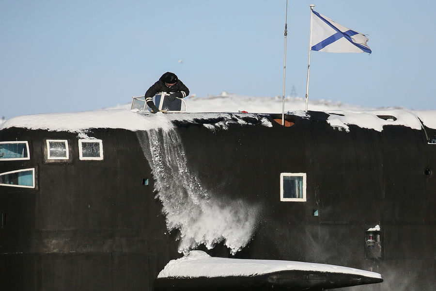 Один из членов экипажа очищает от снега рубку атомного ракетного подводного крейсера стратегического назначения проекта 667БДРМ «Дельфин» К-18 «Карелия» на причале в Мурманской области, 2021 год 