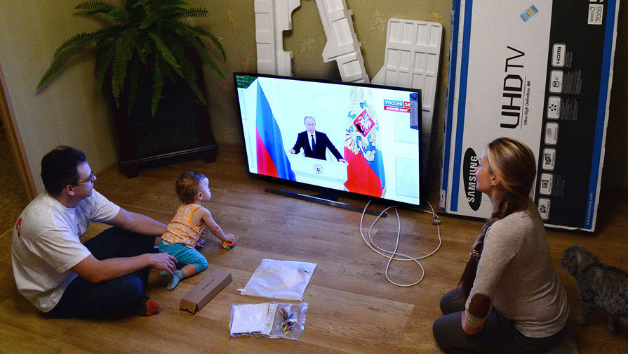Молодая семья во Владивостоке смотрит телевизионную трансляцию послания президента РФ Владимира Путина к Федеральному Собранию