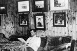 Николай II сидит на диване в своей комнате в охотничьем домике и читает книгу
