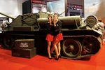 Модели в тематических костюмах позируют возле танка на стенде видеоигры «War Thunder» на выставке Gamescom в Кельне