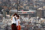 Пара на фоне Национального Олимпийского стадиона, главной площадки Олимпийских игр 2020 года в Токио, 19 июля 2021 года