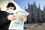 Жительница Венеции читает свежую газету на площади у Кафедрального собора в Милане, который был закрыт в связи с вспышкой коронавируса в Италии, 24 февраля 2020 года