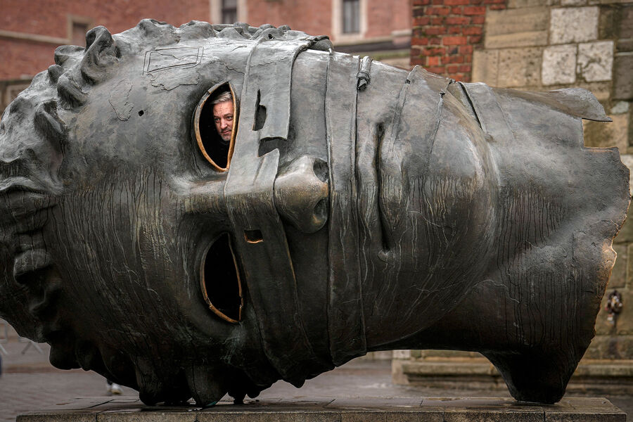 Мужчина выглядывает из&nbsp;головы «Связанного Эрососа» &mdash; скульптуры Игоря Миторая, установленной в&nbsp;центре Кракова, Польша, 10&nbsp;ноября 2022&nbsp;года