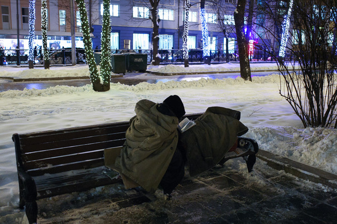 Бездомный житель города читает книгу на скамейке на Страстном бульваре