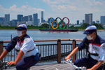 Сотрудники безопасности на фоне понтона с олимпийскими кольцами в Токийском заливе, 20 июля 2021 года
