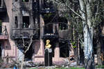 Памятник писателю Владимиру Короленко у разрушенного жилого дома в центре Мариуполя, 28 апреля 2022 года