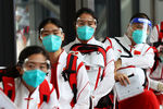 Сборная Китая в защитных масках после прибытия в международный аэропорт Нарита перед Олимпийскими играми 2020 года в Токио, 19 июля 2021 года