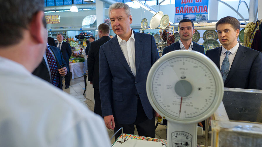 Мэр Москвы Сергей Собянин (слева) разговаривает с продавцом во время посещения Ленинградского сельскохозяйственного рынка в Северном административном округе Москвы