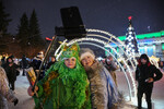 Женщины в костюмах зеленого дракона и Снегурочки фотографируются во время празднования Нового года на площади Ленина в Новосибирске