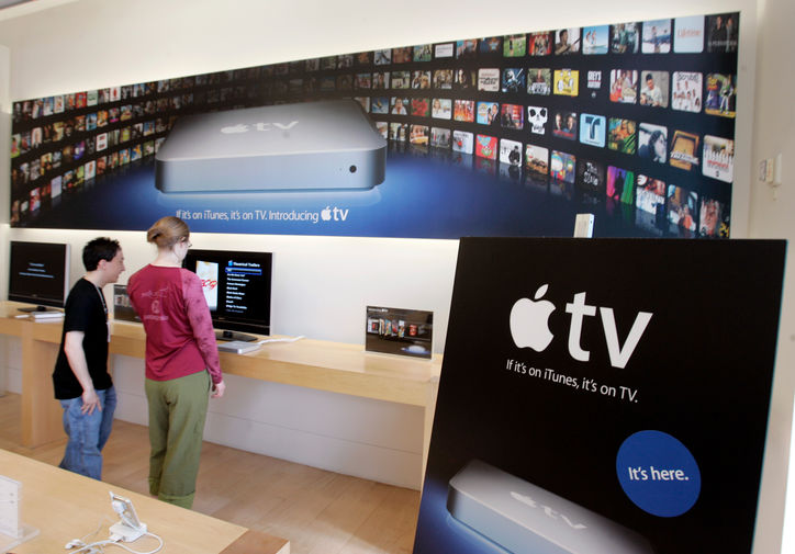 <b>Apple TV (2007)</b><br><br>
В надежде доставить iTunes в каждую гостиную в 2007 году Apple представила Apple TV — приставку, подключающуюся к телевизору пользователя. Этот продукт все еще выпускается компанией, но имеет более современные функции, нежели самая первая модель — в частности, в 2017 году миру была представлена Apple TV 4K с поддержкой видео в формате 4К. На фото реклама приставки в фирменном магазине компании в Пало-Алто в 2007 году