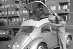 Девушка демонстрирует контейнер, установленный на крыше автомобиля Volkswagen Beetle, который обеспечивает дополнительное место для багажа на Международной выставке пластмасс в Дюссельдорфе, Германия, 1959 год