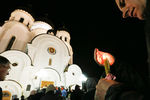 Мужчина держит зажженную свечу перед церковью Рождества Христова в Красноярске