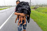 Мужчина с детьми ищет укрытие после того, как ураган «Иан» затопил его дом в Пинар-дель-Рио, Куба, 27 сентября 2022 года