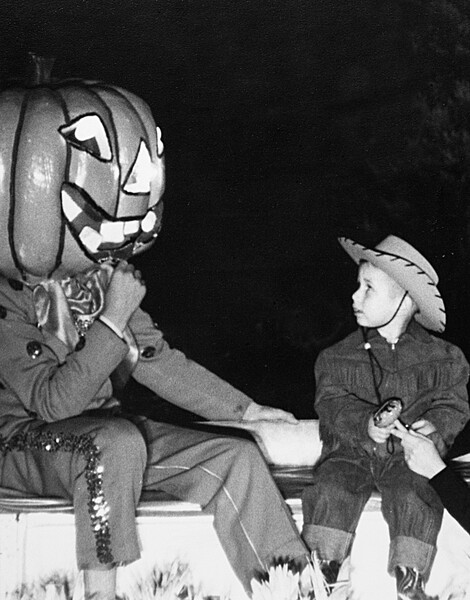 Мужчина в костюме тыквы и мальчик в костюме ковбоя на вечеринке в честь Хэллоуина, примерно 1955 год