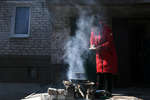 Женщина готовит еду на костре во дворе жилого дома в Волновахе, март 2022 года