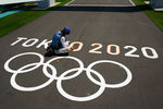 Рабочий красит олимпийские кольца на финише гоночной трассы BMX в рамках подготовки к летним Олимпийским играм 2020 года, 20 июля 2021 