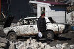 Мужчина проходит мимо автомобиля, уничтоженного в результате обстрела в Волновахе, март 2022 года