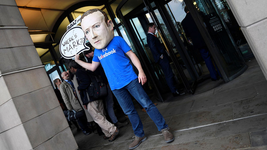 Человек в маске с изображением главы Facebook (компания-владелец Meta признана экстремистской организацией) Марка Цукерберга во время пикета в Лондоне, ноябрь 2018 года