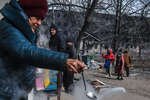 Residents of houses on the outskirts of Mariupol cook in the garden, March 2022