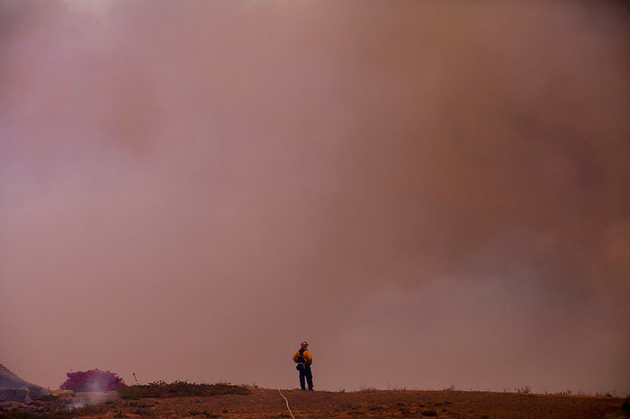 Пожарный стоит среди дыма, Сан-Маркос, Калифорния
