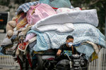 Мужчина управляет тележкой, груженной постельными принадлежностями, Пекин, 16 июня 2022 года