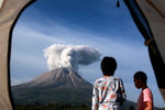 Туристы наблюдают из палатки, как извергается вулкан Синабунг в провинции Северная Суматра, Индонезия, 11 марта 2021 года