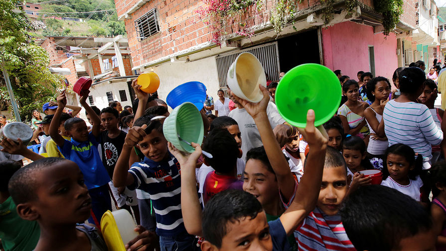 Дети стоят в очереди за бесплатной едой в бедном районе Каракаса, сентябрь 2016 года