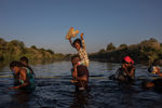 Мигранты из Гаити идут через реку Рио-Гранде на границе США и Мексики, 19 сентября 2021 года