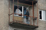 Жители города Дебельцево закрывают полиэтиленовой пленкой окна и балкон с выбитыми стеклами в одном из пострадавших в результате обстрелов во время боевых действий жилых домов
