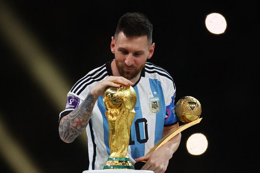 Аргентинский футболист Лионель Месси гладит кубок мира ФИФА, 18 декабря 2022 года