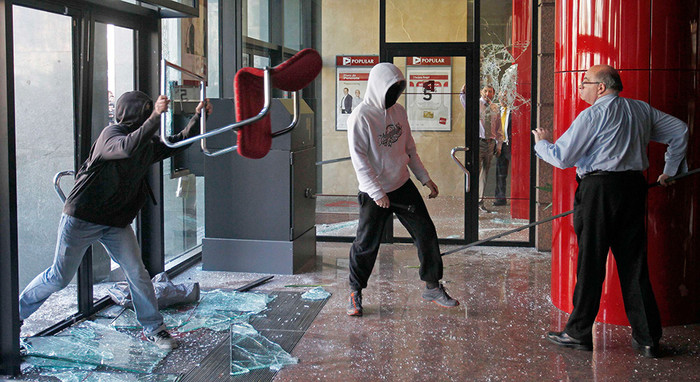 29&nbsp;февраля. Клерк защищает помещение банка в&nbsp;Барселоне от вандалов во время массовых протестов против сокращения бюджетного финансирования в&nbsp;сфере образования.