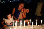 Женщина плачет над свечами, зажженными в память о погибших, Малайзия