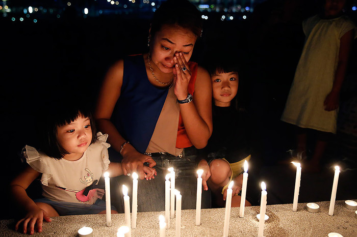 Женщина плачет над&nbsp;свечами, зажженными в&nbsp;память о&nbsp;погибших, Малайзия