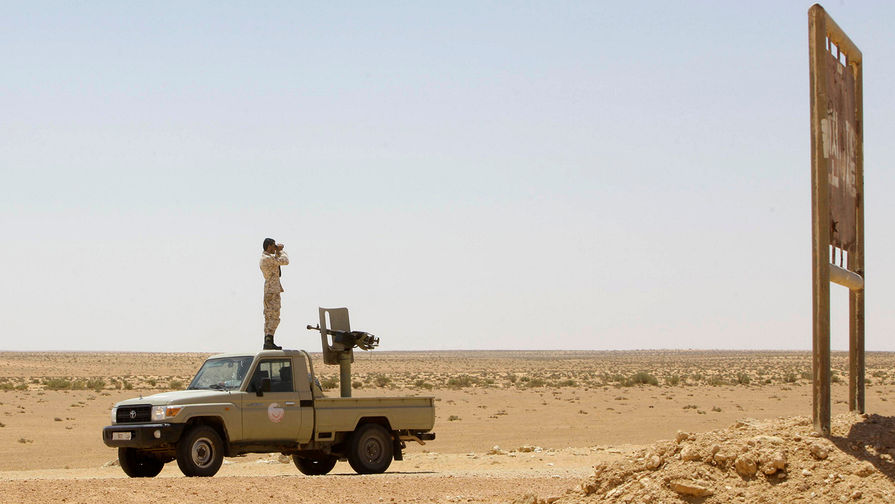 Солдат ливийской армии смотрит в бинокль во время патрулирования территории на окраине города Сирт 