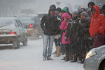 Жители города на остановке общественного транспорта во время сильного снегопада