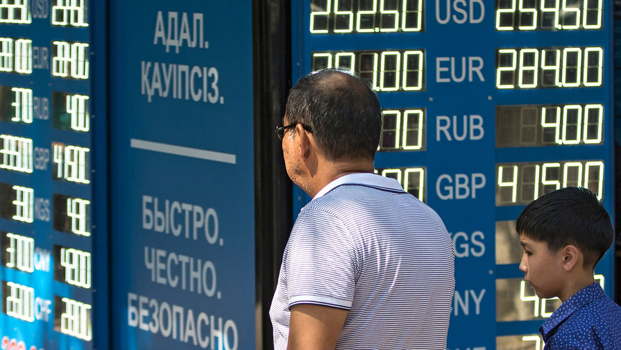 Мужчина с ребенком у информационного табло обменного пункта валюты в Алма-Ате.
