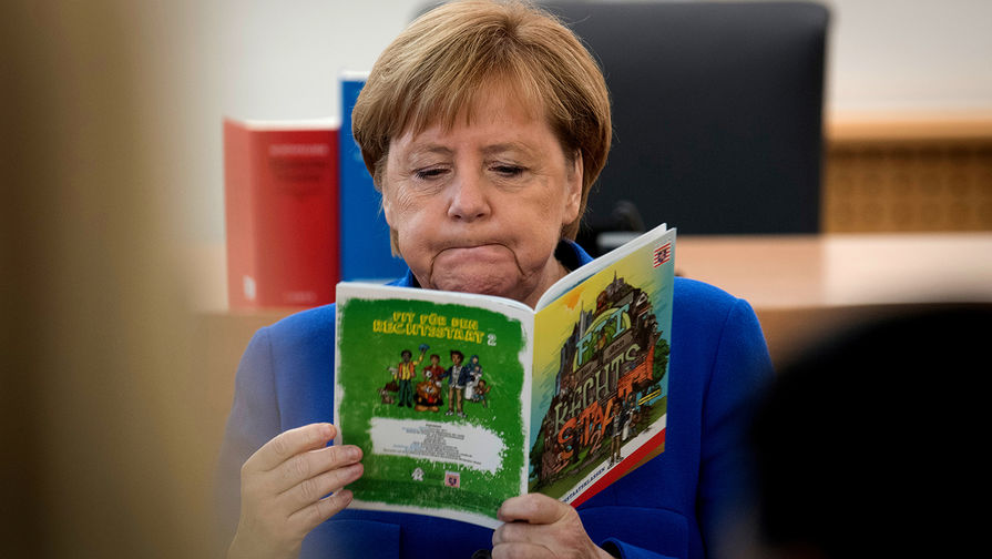 Канцлер ФРГ Ангела Меркель с брошюрой во время посещения занятий для мигрантов во Франкфурте, октябрь 2018 года