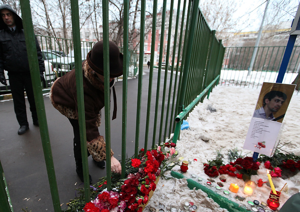 Женщина возлагает цветы у московской школы №263 в Отрадном