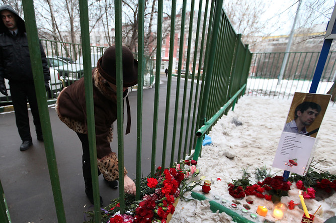 Женщина возлагает цветы у московской школы №263 в Отрадном