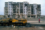 Остатки бронетехники и разрушенный дом в городе Грозном во время Чеченского конфликта 1994-1996 годов