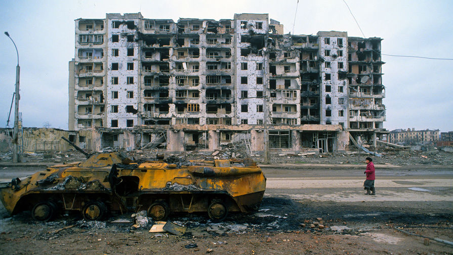 Остатки бронетехники и разрушенный дом в городе Грозном во время Чеченского конфликта 1994-1996 годов