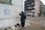 Жительница города Дебальцево готовит еду на костре на улице у жилого многоквартирного дома, пострадавшего в результате обстрелов во время боевых действий