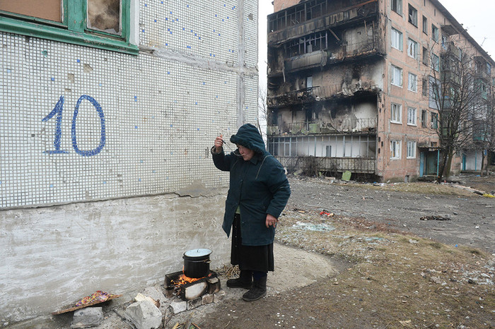 Жительница города Дебальцево готовит еду на&nbsp;костре на&nbsp;улице у&nbsp;жилого многоквартирного дома, пострадавшего в&nbsp;результате обстрелов во время боевых действий